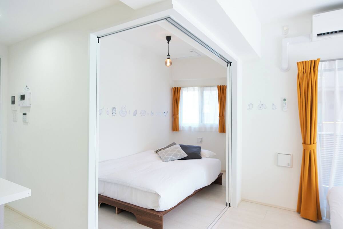 A modern bedroom with a bed, a bedside table, a wardrobe, and a window with curtains.
