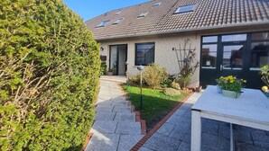 A residential house with a tiled roof, a paved driveway, and a well-maintained garden. - Vacation apartment "Still Hörn 3" in Greetsiel (approx. 35 sqm / 2 persons) (Krummhörn)