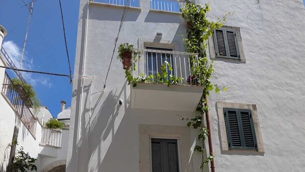 A white building with a grey door, numbered 22, and a small garden area with potted plants. - Charming 1-bedroom house in adorable Putignano with WiFi, AC (Putignano)