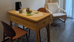 A hotel room with a dining table, chairs, a coffee maker, and a chair with a cushion. - Charming 1-bedroom house in adorable Putignano with WiFi, AC (Putignano)