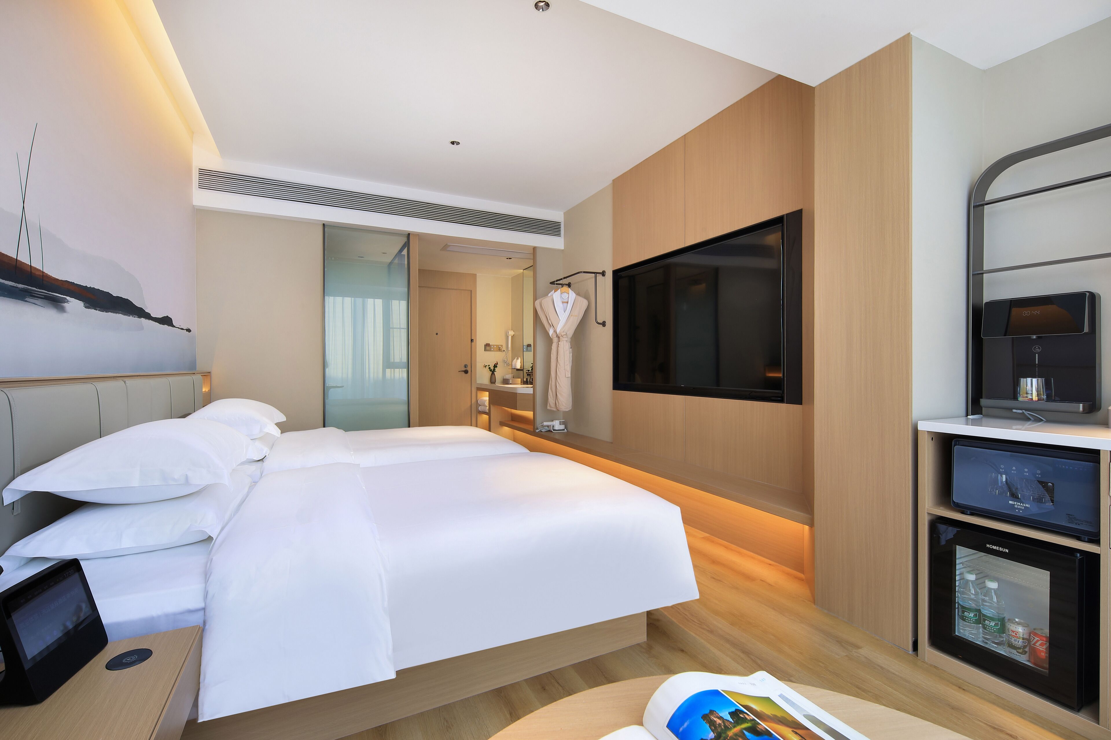 Une chambre d’hôtel moderne dotée d’un grand lit, d’une télévision à écran plat, d’un minibar et d’une porte coulissante donnant accès à la salle de bain.
