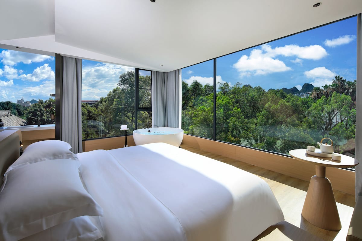 Un dormitorio moderno con una cama grande, una bañera y una mesita con un hervidor.