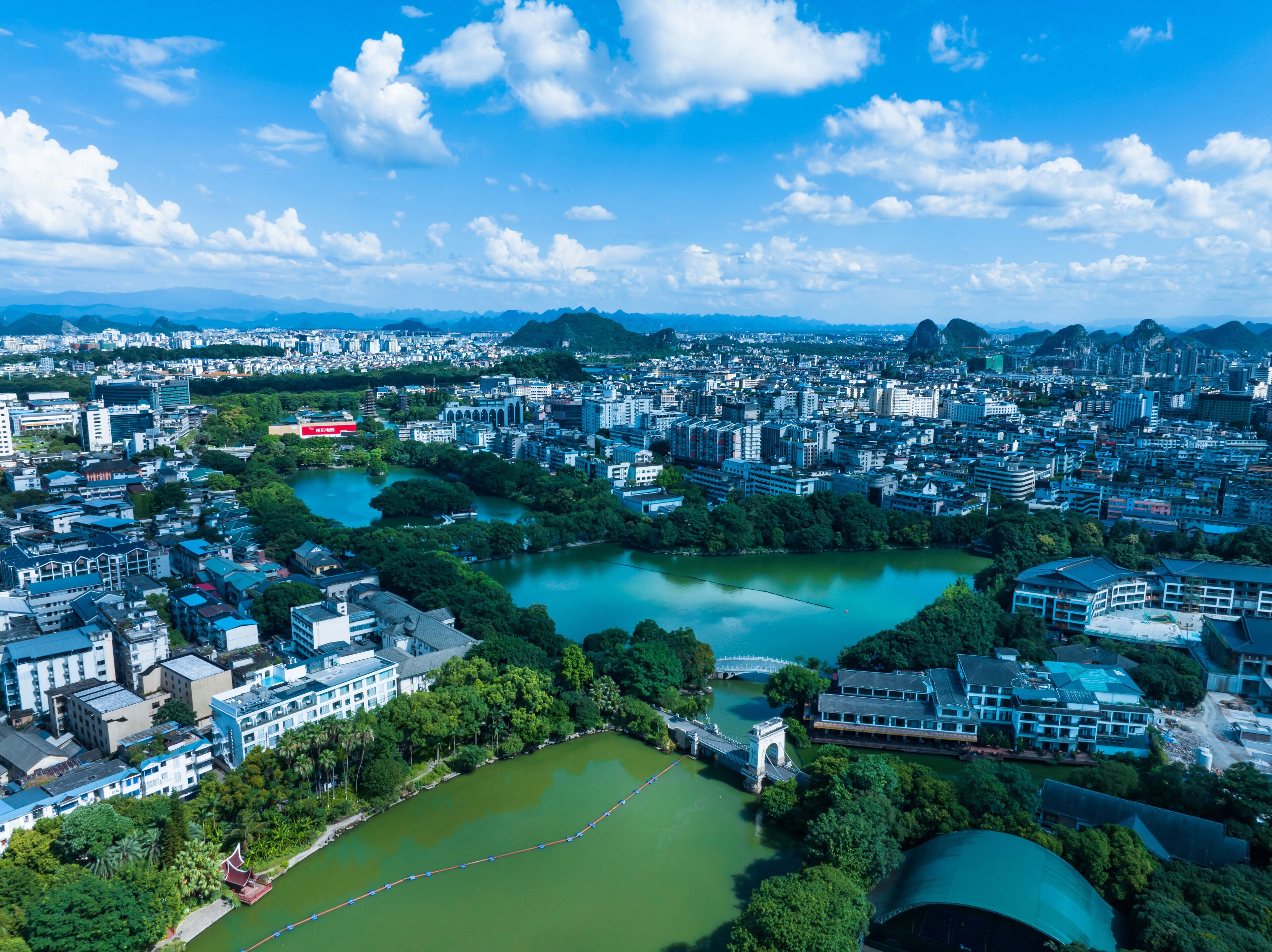 An aerial view of a city with dense urban development, a river, and surrounding greenery.