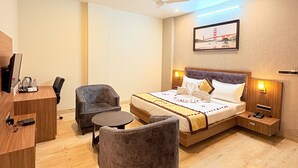 A hotel room with a bed, a desk, a chair, a small table, and a ceiling fan. - Parampara Hotels And Resorts (Udaipur)