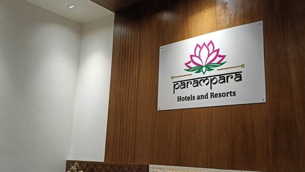 A reception area with a wooden panel wall, a marble reception desk, and a sign for Parapara Hotels and Resorts. - Parampara Hotels And Resorts (Udaipur)