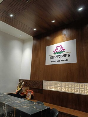 A reception area with a wooden panel wall, a marble reception desk, and a sign for Parapara Hotels and Resorts. - Parampara Hotels And Resorts (Udaipur)