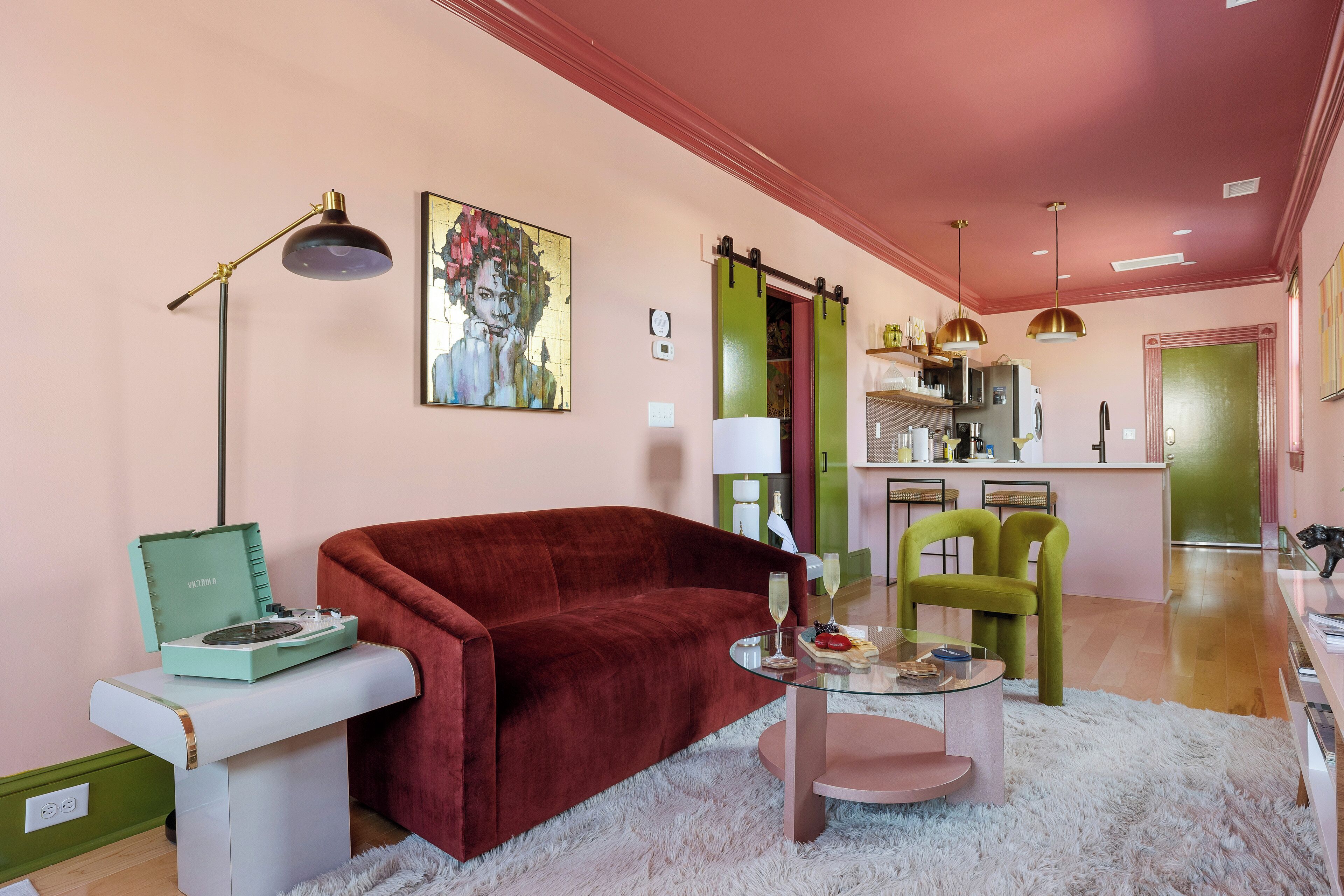 A living room with a red sofa, a glass coffee table, a vintage record player, and a green chair.