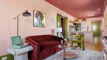 A living room with a red sofa, a glass coffee table, a vintage record player, and a green chair.
