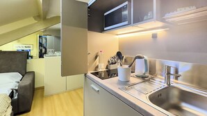 A compact kitchenette with a microwave, sink, and storage cabinets. - BRERA - Tiny Studio (Milano)