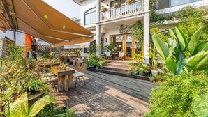 A wooden deck with outdoor seating, surrounded by lush greenery and potted plants.