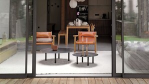 A modern interior with a wooden ceiling, a dining area with a table and chairs, and a kitchen visible through glass doors.