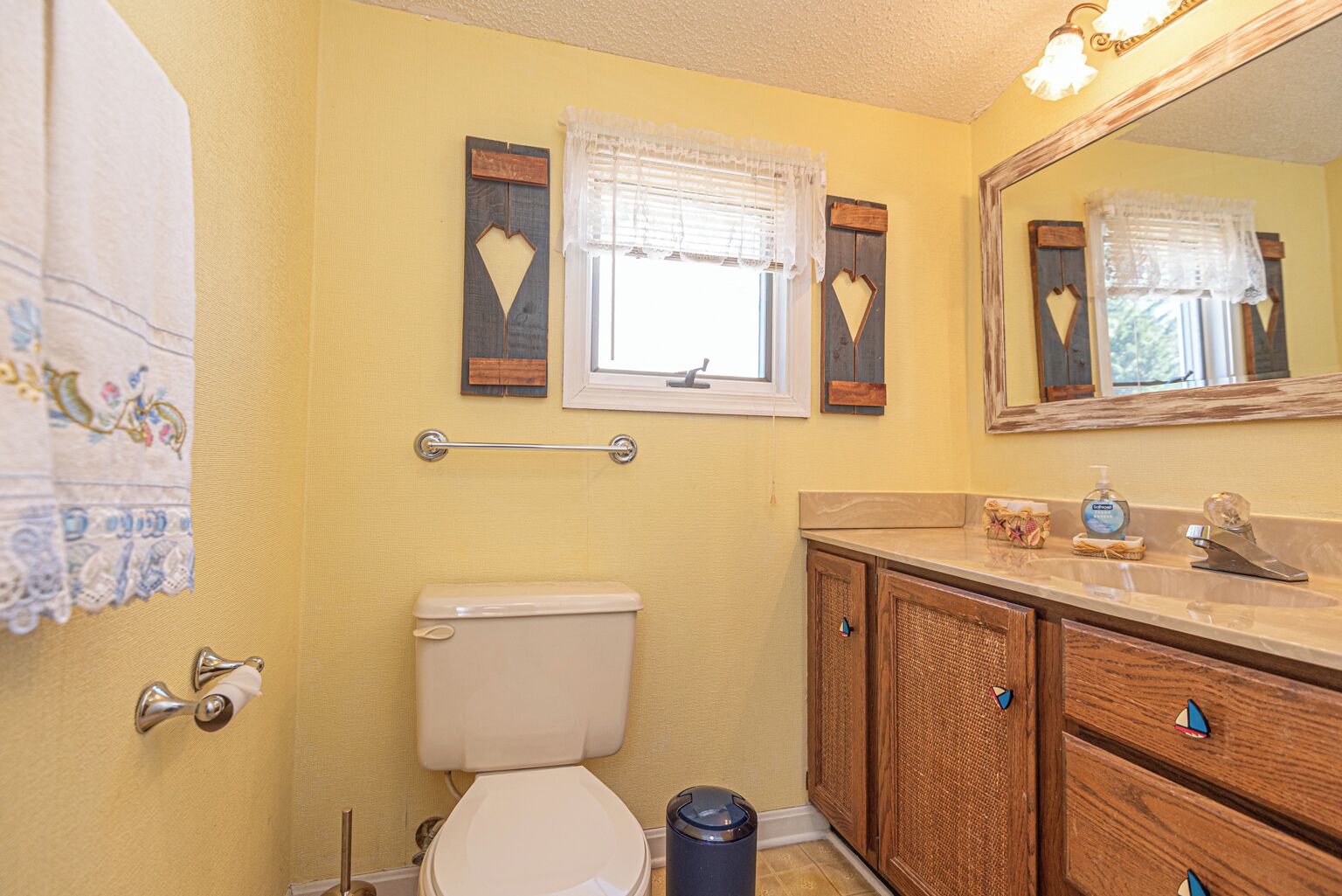 A bathroom with a toilet, vanity, and a mirror.
