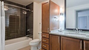 Un baño moderno con bañera, inodoro y armarios de madera.