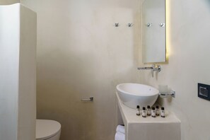A bathroom with a white toilet, a white sink with a mirror above it, and a towel hanging on the wall.