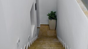 A narrow, white-walled stairway with a potted plant at the bottom. - Dream of Paros by GHH (Paros)