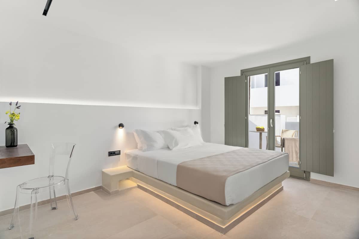 A modern bedroom with a bed, bedside table, and a clear chair.
