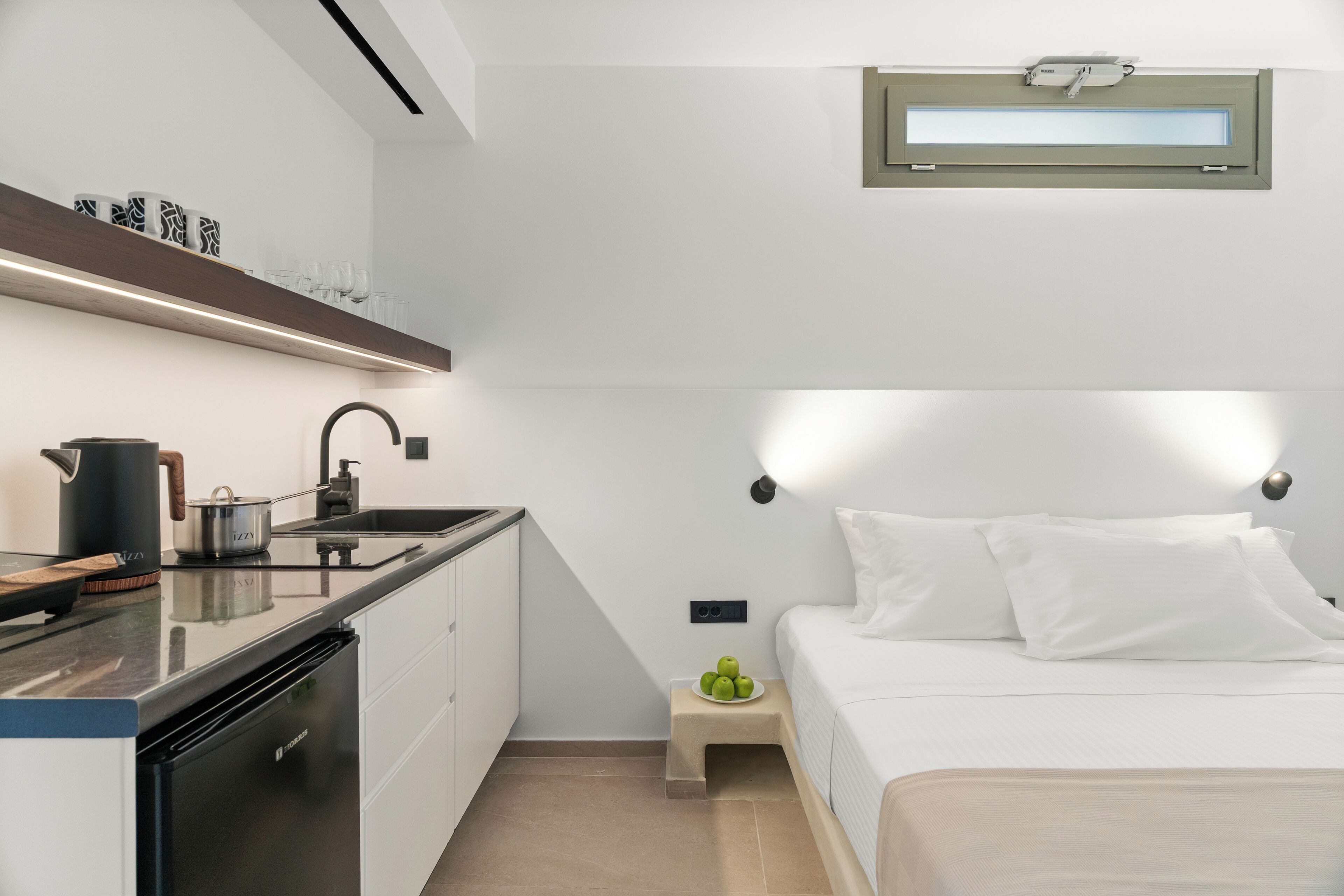 A compact bedroom with a bed, bedside table, and a small window.
