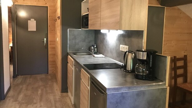 Una cocina funcional con armarios de madera, encimera de acero inoxidable, un fregadero y una cafetera.