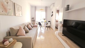 Un salon moderne avec un canapé, un téléviseur et un coin repas.