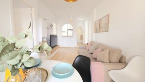 Un vaste espace de vie comprenant un canapé, une table à manger dressée avec des assiettes et des verres, et un téléviseur en arrière-plan.