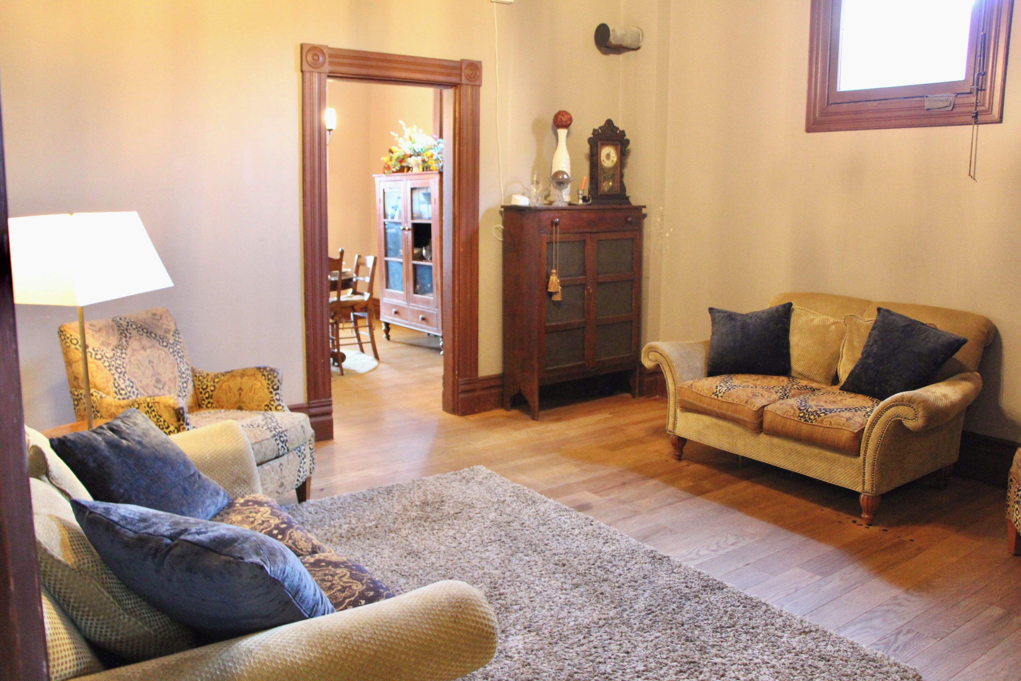 Una sala de estar con un sofá, sillones, un tapete y un aparador.
