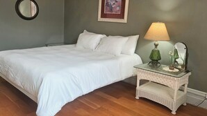 Un dormitorio con una cama, una mesita de noche, una lámpara, un espejo y un cuadro en la pared.