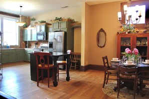 Una cocina con armarios de madera, una mesa de comedor para cuatro personas y una araña.