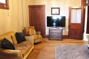 Un salon avec un canapé, un téléviseur et un meuble en bois.