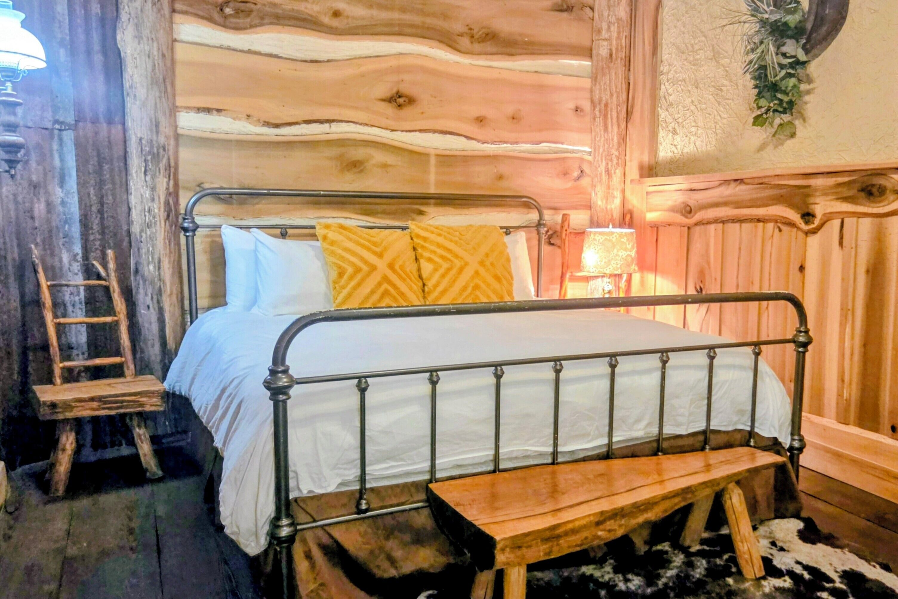 L’intérieur d’une cabane en bois, avec un cadre de lit en métal, une échelle et un banc.