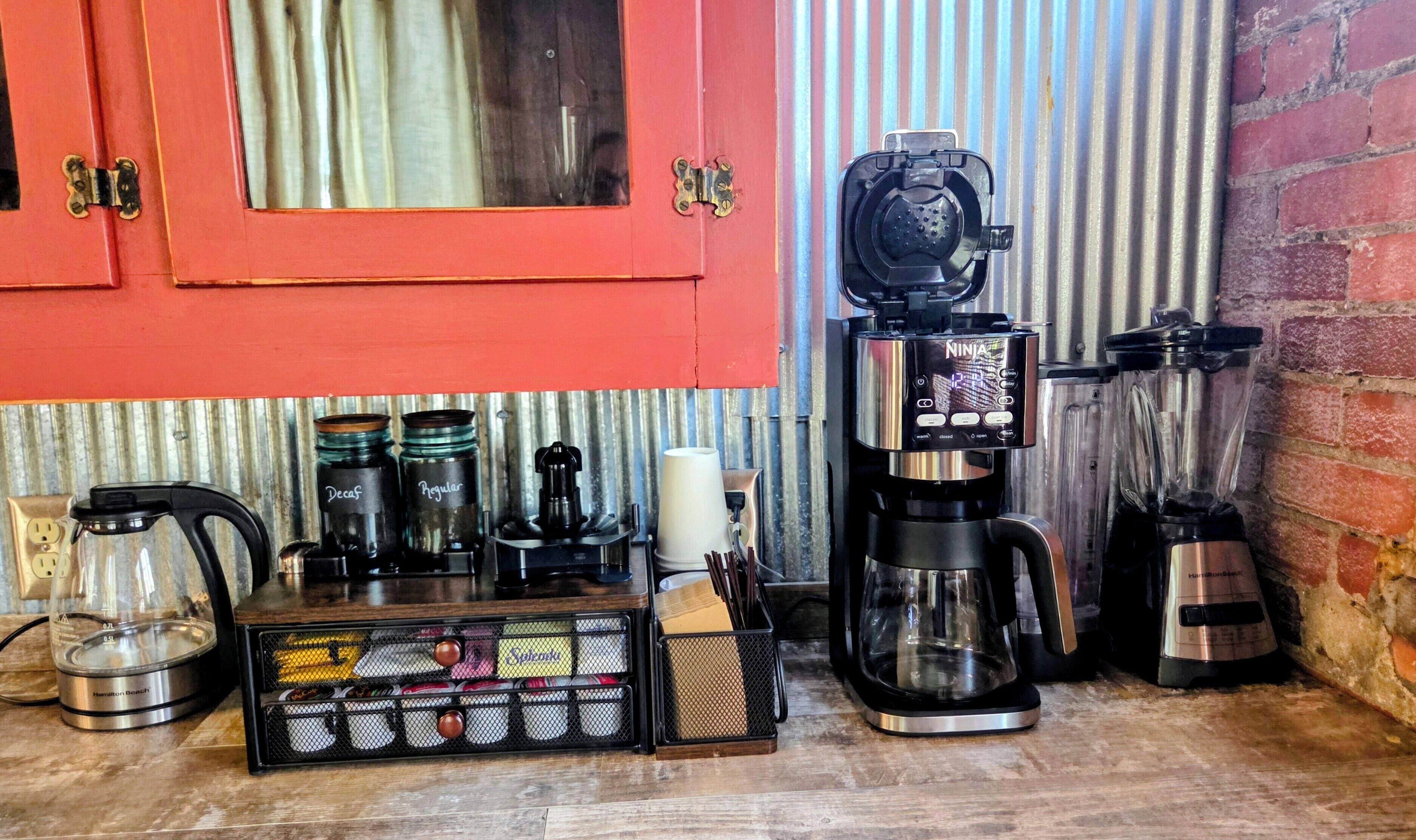 A kitchen with a coffee maker, blender, and various kitchen utensils.