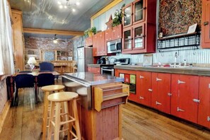 Una cocina con armarios de madera, una isla de acero inoxidable y una pared de ladrillo.