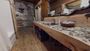 Un baño rústico con encimera de piedra, lavabo de madera y espejo con un marco ornamentado.