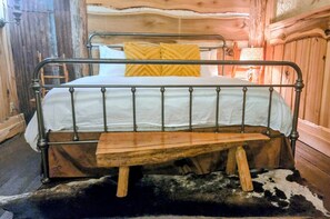 Una cama litera con estructura metálica y una banca de madera unida a la cama inferior.