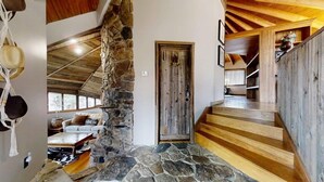 Un intérieur rustique avec une cheminée en pierre, un escalier en bois et un coin salon confortable.
