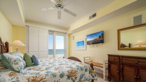 Ein Schlafzimmer mit Bett, Kommode, Stuhl, Deckenventilator und einem Fenster mit Blick.