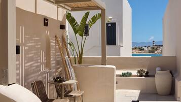 A sunlit outdoor seating area with a table, chairs, and a potted plant.