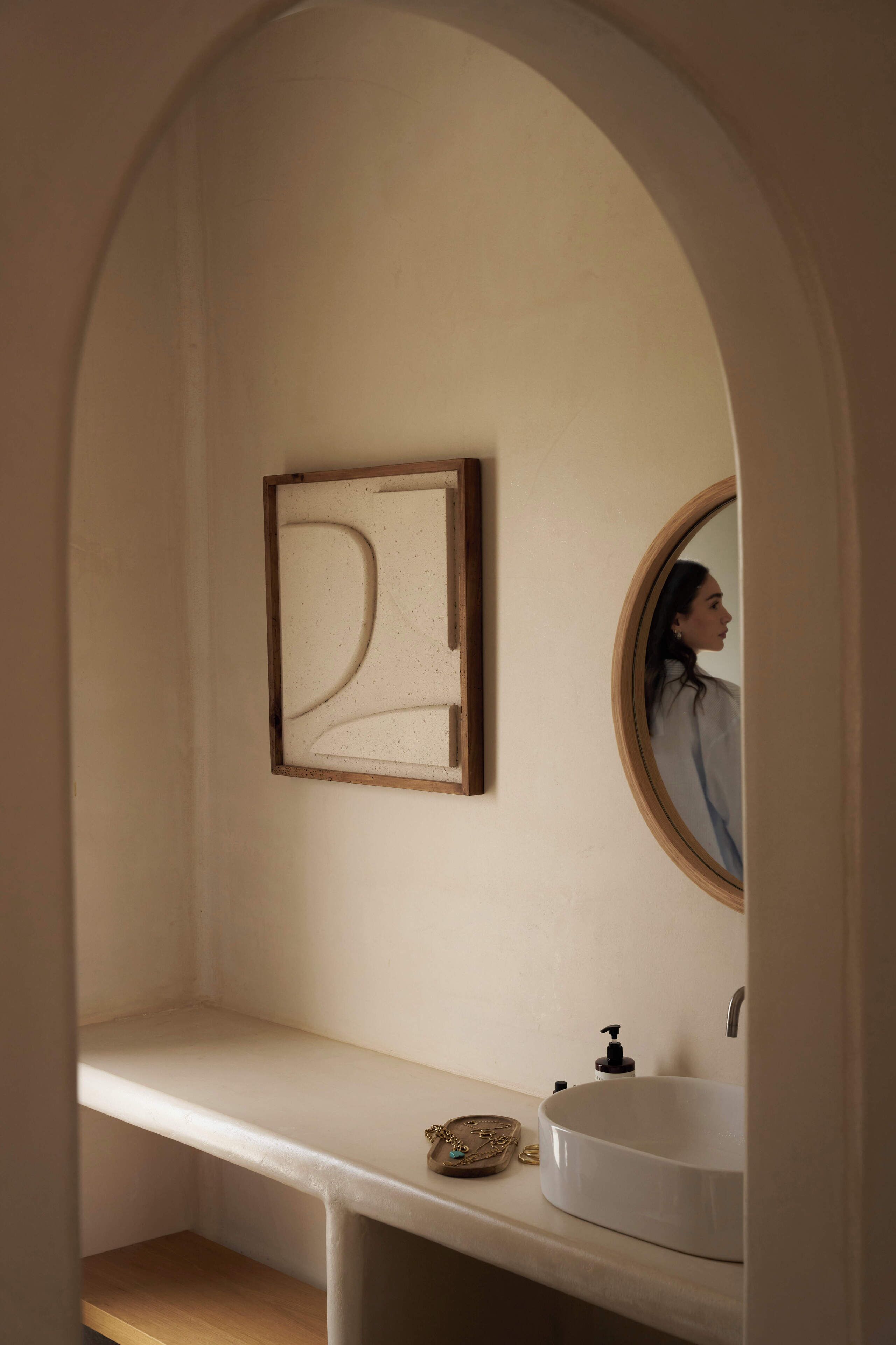 Une salle de bain avec un lavabo blanc, un miroir et une œuvre d’art encadrée accrochée au mur.