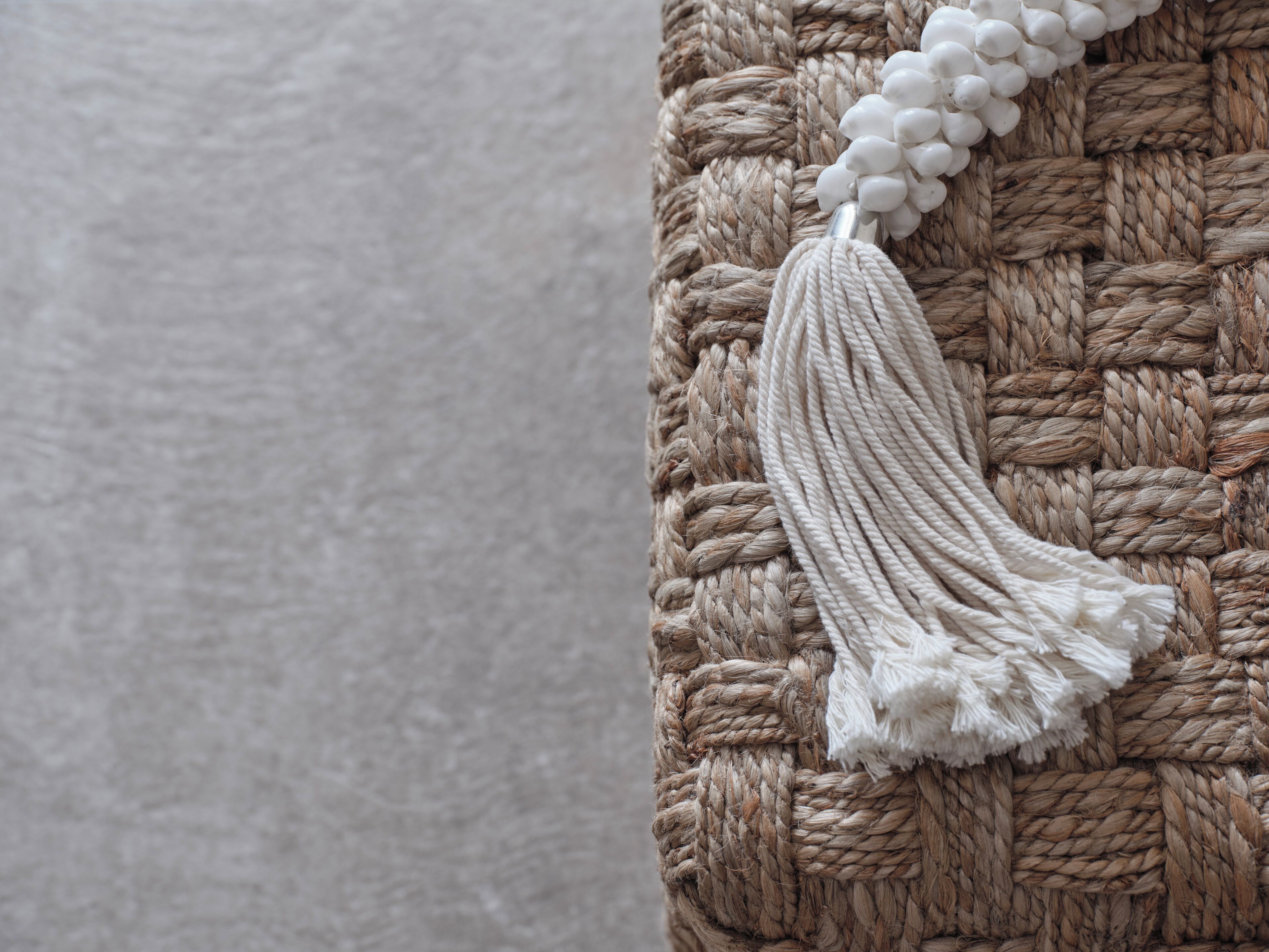 A close-up of a textured woven fabric with a white tassel.