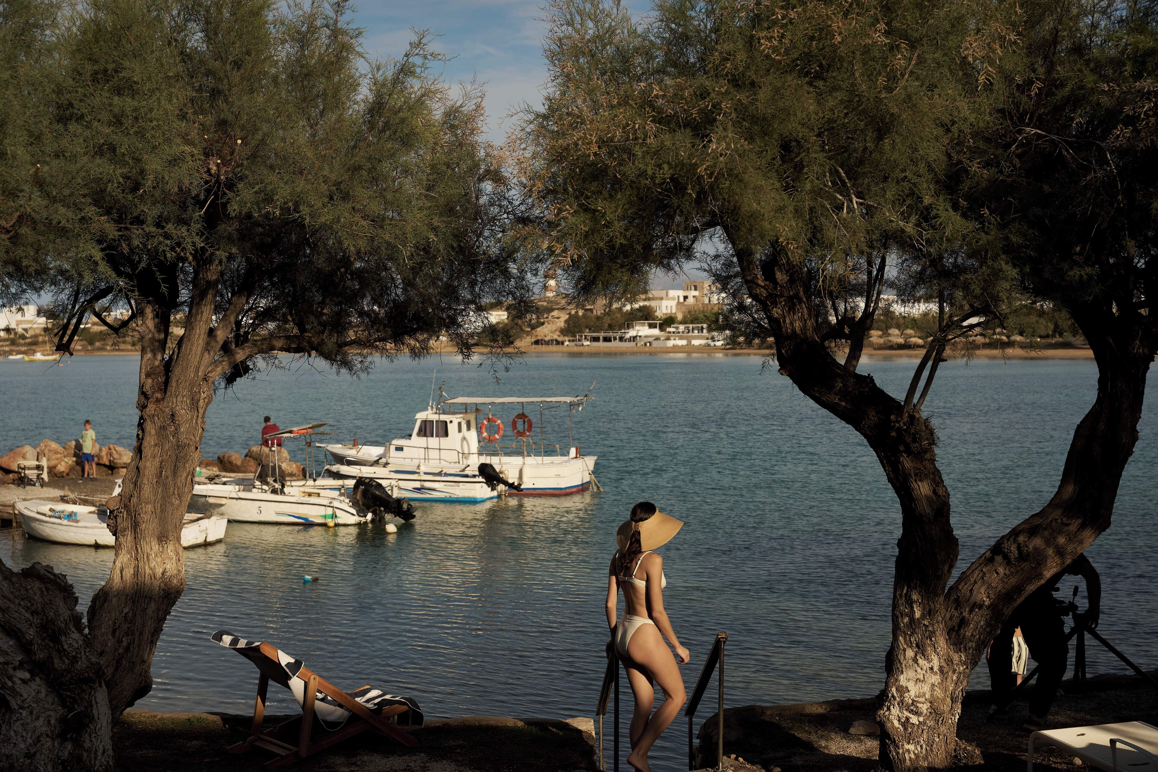 A coastal scene with boats docked, a beach chair, and a person standing by the water.