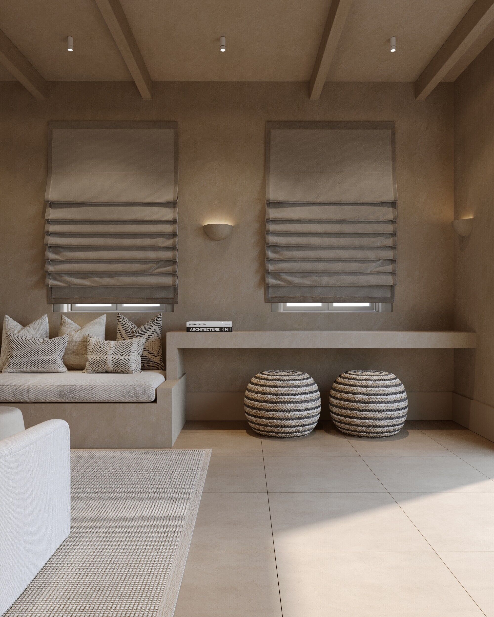 A modern living room with a sofa, two round ottomans, and a bookshelf.