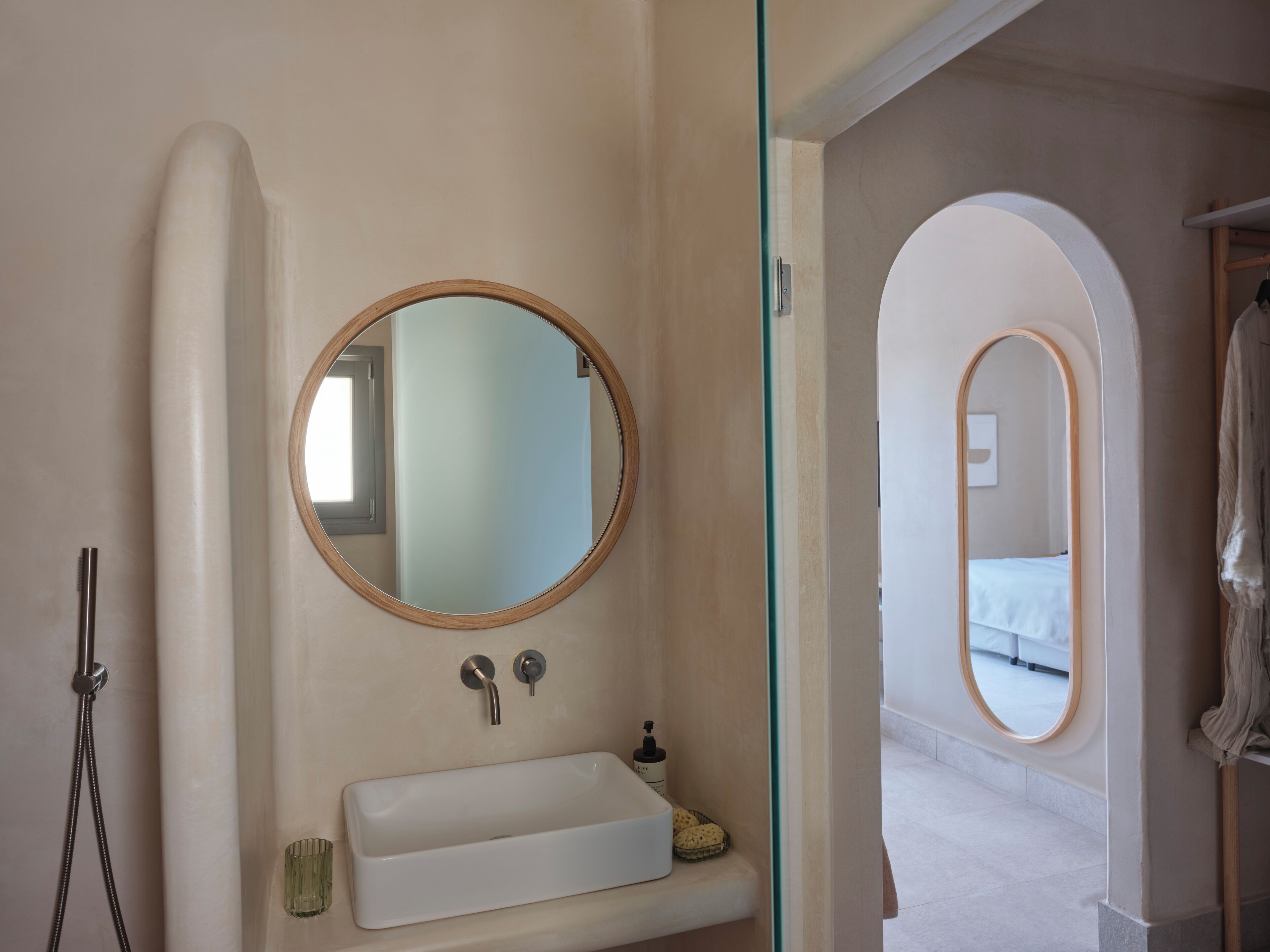 A bathroom with a round mirror, a rectangular sink, and a shower.