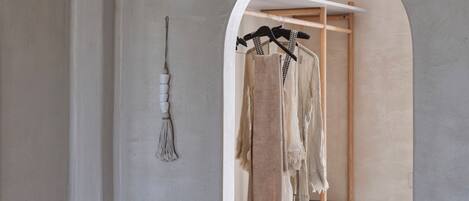 A minimalist closet with a wooden hanger rack and a hanging rack.