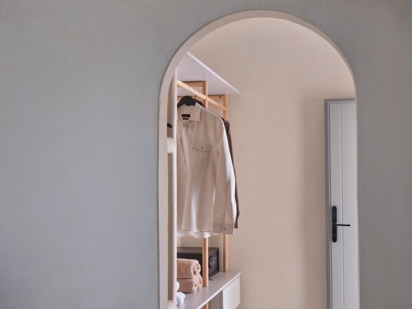 A room with a white door, a white wardrobe, and a hanging rack with clothes. - Salt Suites Paros (Paros)
