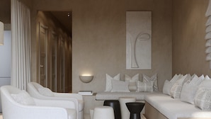 Una sala de estar moderna con un conjunto de sofás, una mesa de centro y una mesita auxiliar. Se observa una obra de arte colgada en la pared y una lámpara de pie.