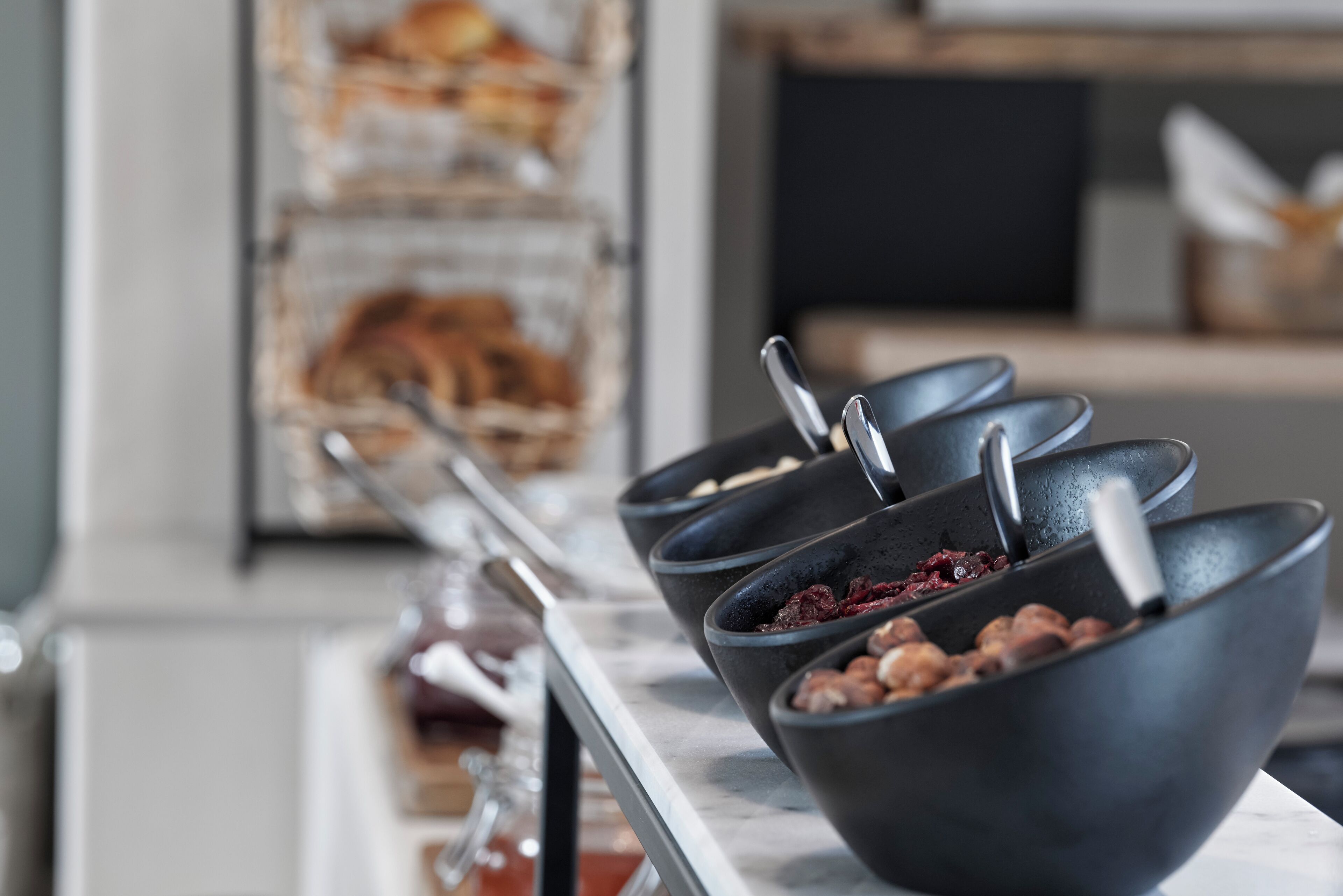 Uma mesa de buffet com recipientes de comida, incluindo frutos secos e frutas desidratadas.