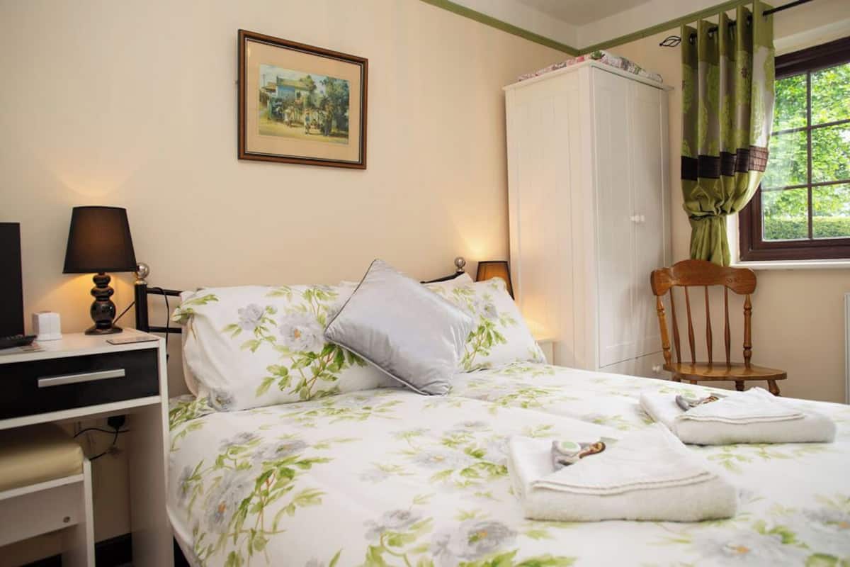Ein Schlafzimmer mit Bett, Schreibtisch, Stuhl, Kleiderschrank und einem fensterbepflanzten Fenster.