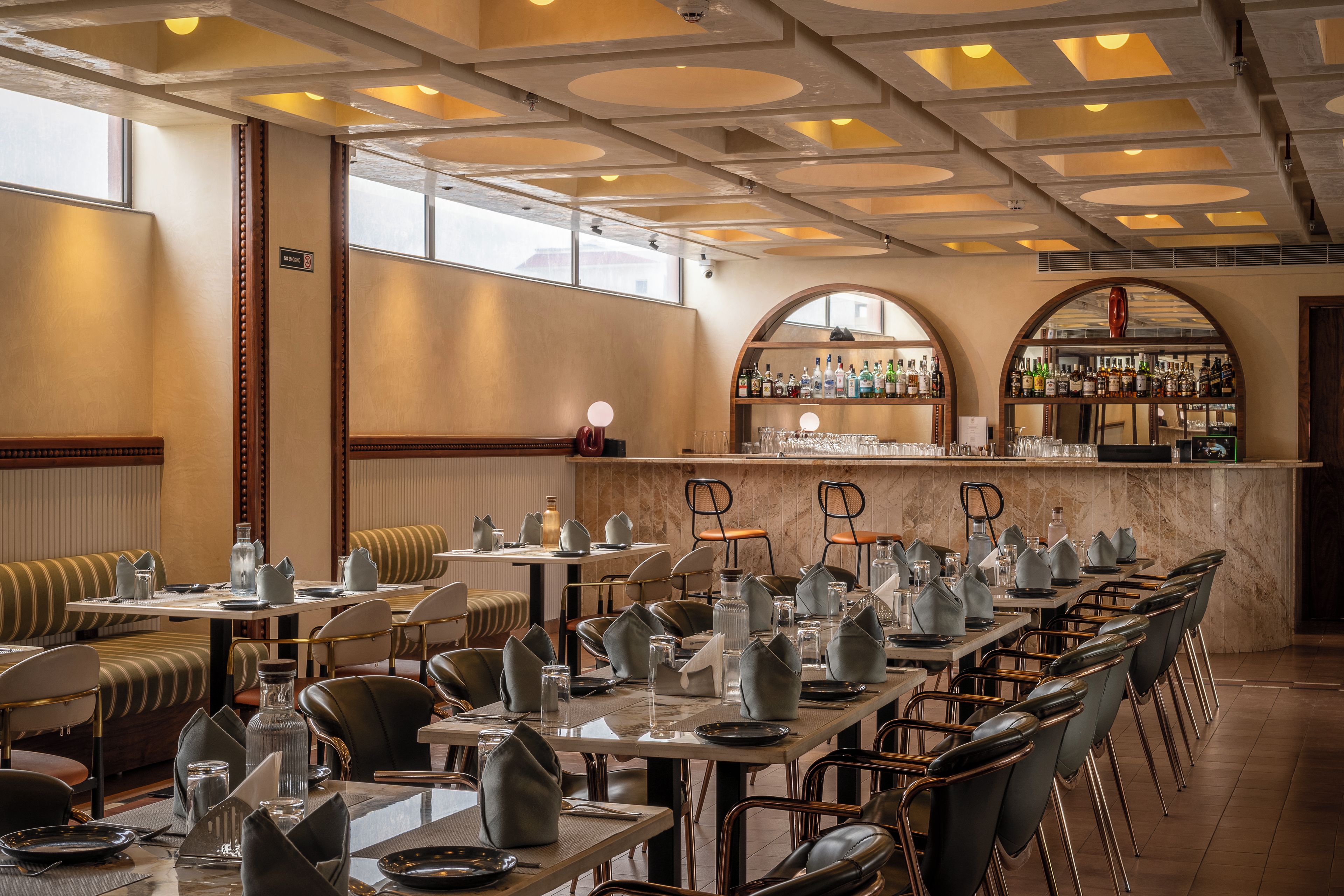 A restaurant with high tables, chairs, and a bar area.