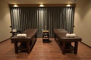 A room with two massage tables, each with a towel and a small shelf with bottles. - Tree of Life Ganga Dwar, Haridwar (Haridwar)