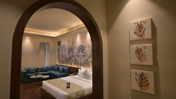 Habitación de hotel con cama, sofá, una mesita y una pared decorada con tres obras de arte de motivos vegetales.