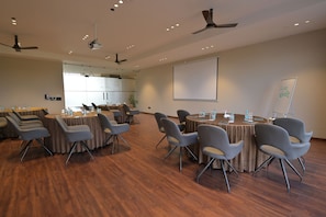 A conference room with multiple tables and chairs, ceiling fans, and a projector screen. - Tree of Life Ganga Dwar, Haridwar (Haridwar)